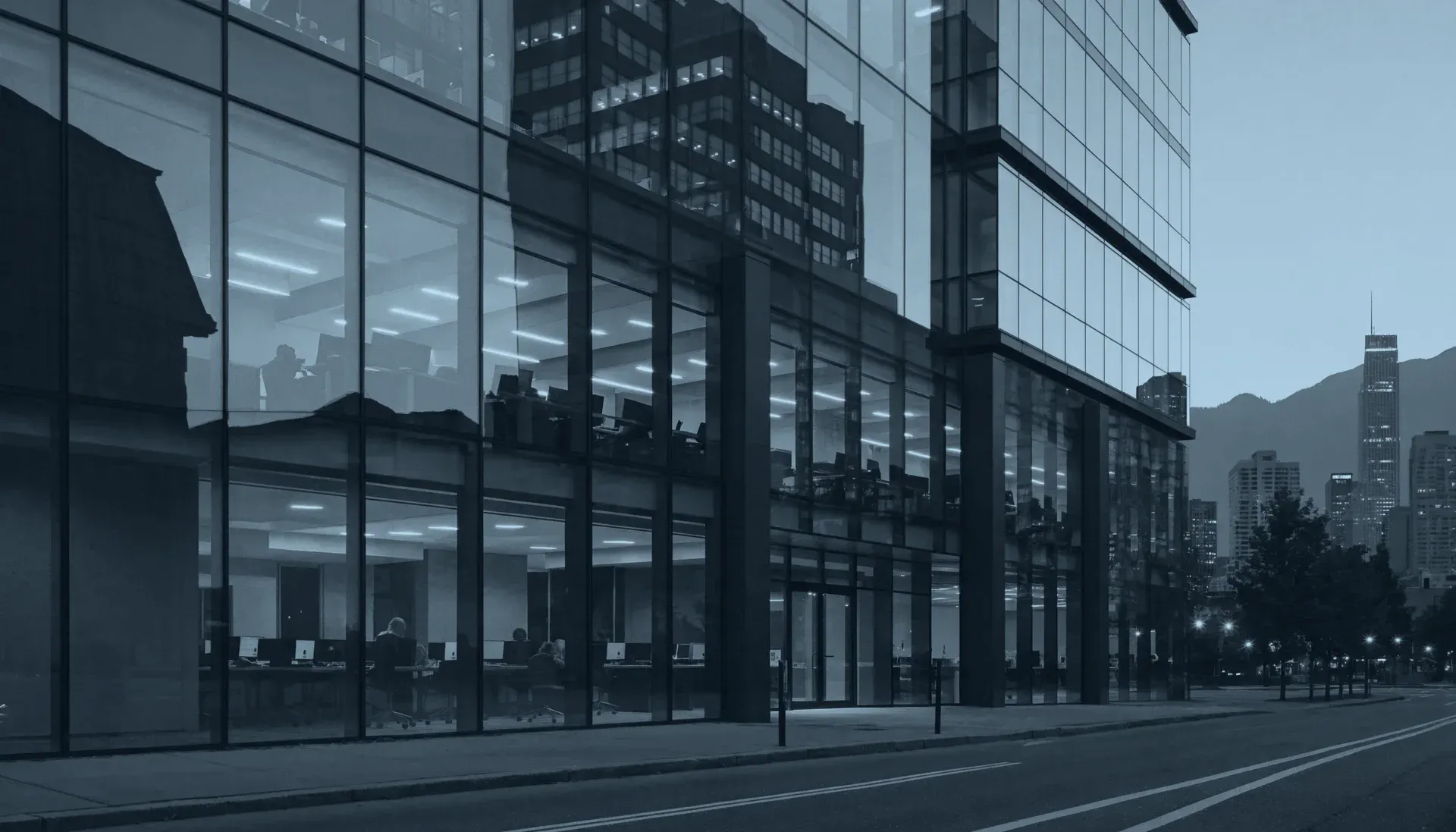 A modern glass office building at dusk