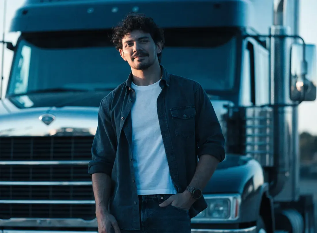 An owner-operator standing beside their truck